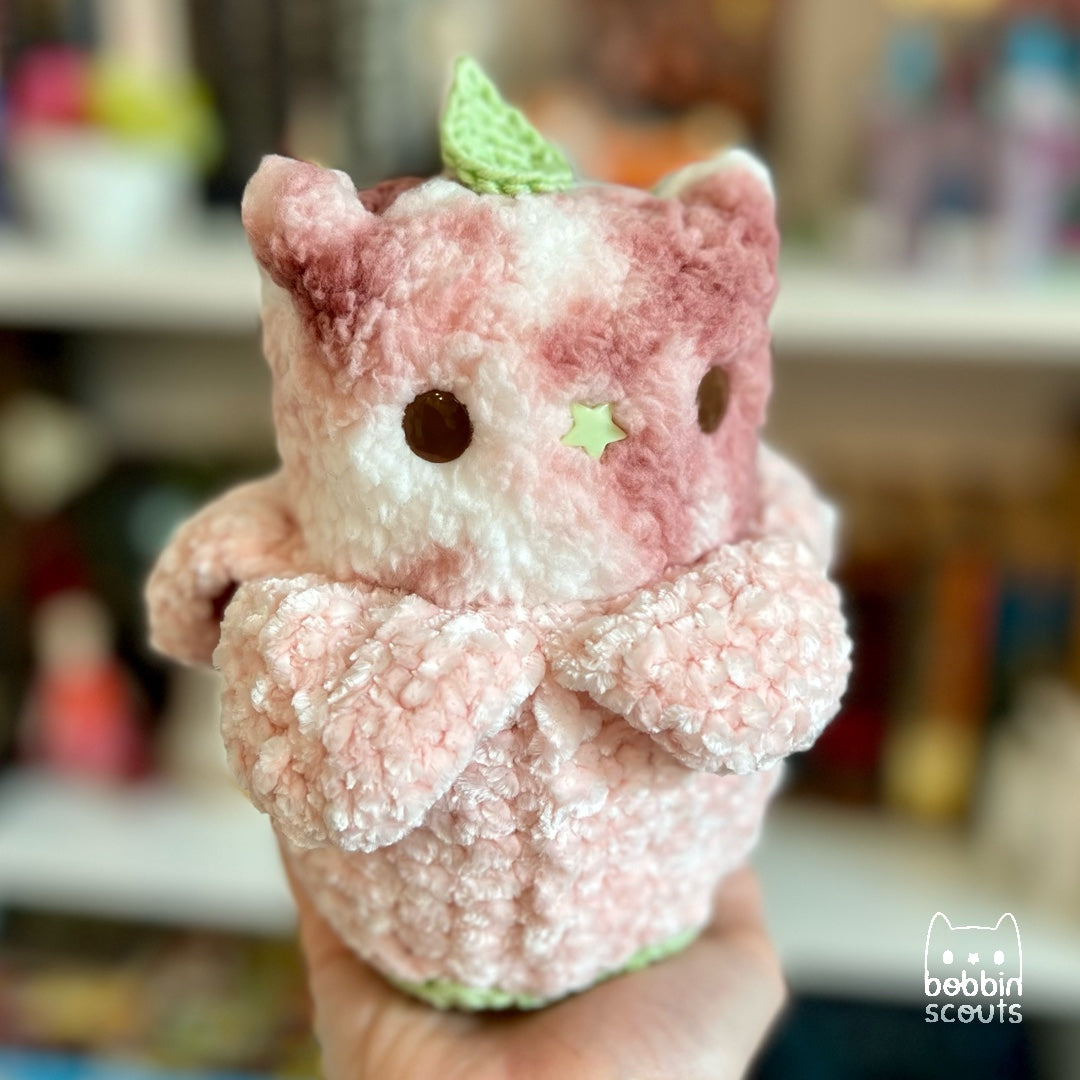 pink tie dyed plushie poking out from a crocheted flower blossom shell